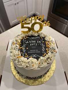 a 50th birthday cake with white frosting and gold sprinkles on top