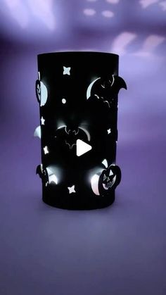 a black cup with white stars and bats on it, sitting in front of a purple background