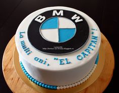 a white and blue cake with the word bmw on it's bottom layer is sitting on top of a wooden board