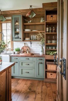 a kitchen with green cabinets and wooden floors