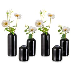 four black vases with white flowers in them on a white background, one is empty and the other has green leaves