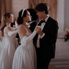 two people in formal wear standing next to each other and one person adjusting the tie