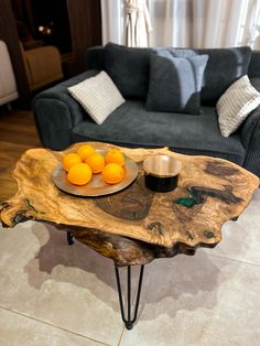 a bowl of oranges sitting on top of a wooden table next to a couch