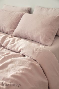 an unmade bed with pink sheets and pillows