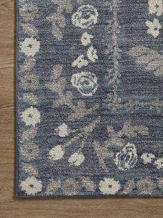 a blue rug with white flowers on the top and bottom, sitting on a wooden floor