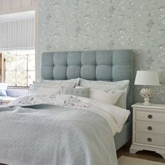 a bedroom with blue and white wallpaper and bed