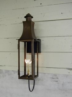 an old - fashioned wall light with two candles lit on the side of a house