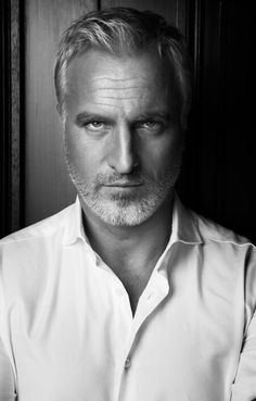 a man in a white shirt is posing for a black and white photo