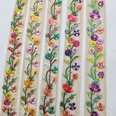 four different colored flowers on white strips with sequins