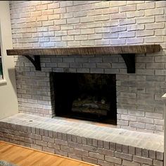 a brick fireplace in a room with hardwood floors