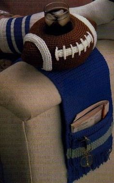 a crocheted football sitting on top of a couch next to a magazine holder