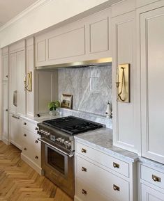 a kitchen with white cabinets and marble counter tops, along with a stove top oven