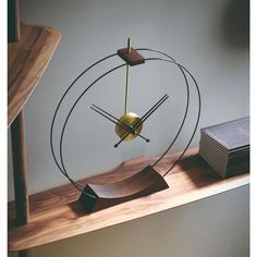 a clock sitting on top of a wooden shelf next to a stack of books and a book