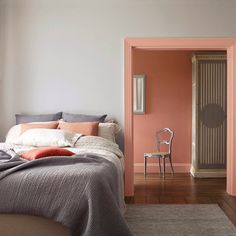 a bed sitting in a bedroom next to a pink wall