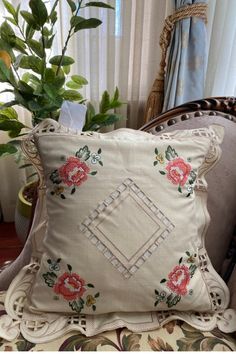 a decorative pillow sitting on top of a chair next to a potted plant