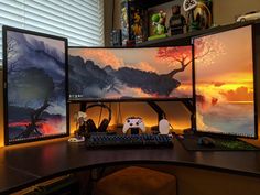 three computer monitors sitting next to each other on top of a wooden desk in front of a window