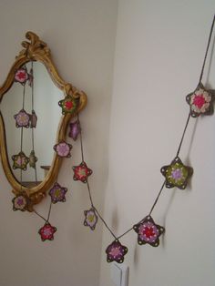 a mirror hanging on the wall next to a flowered garland with pink and green flowers