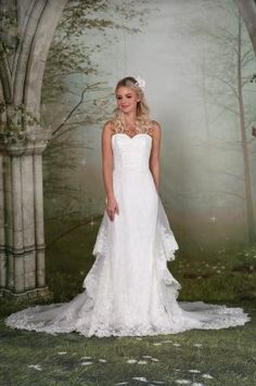 a woman in a white wedding dress standing in front of an archway with flowers on it