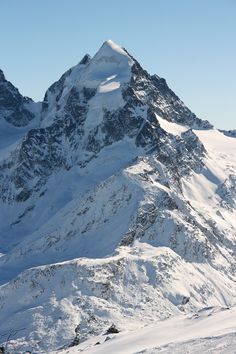 a snow covered mountain is shown in the distance with skis on it's feet