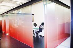 an office cubicle with glass walls and red partitions