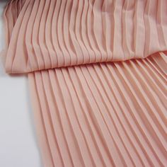 the pleated fabric is pink and has been folded up to show it's folds