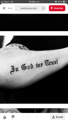 a black and white photo of a man's arm with the words in god we trust on it