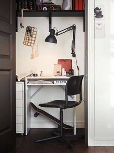 a desk with a chair and a lamp on top of it in front of a door