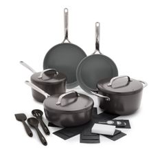 an assortment of black pots and pans with utensils on a white background