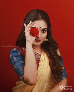 a woman holding a rose in front of her face and looking at the camera with an evil look on her face