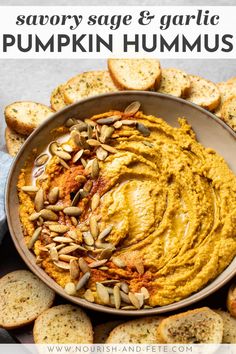 a bowl filled with pumpkin hummus surrounded by crackers and sliced pumpkins on the side