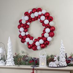 a christmas wreath on a mantel decorated with red and white ornaments