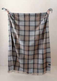 a plaid blanket with fringes hanging from the side on a white wall in an empty room