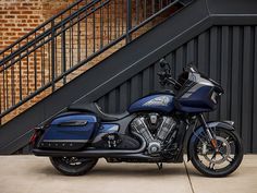 a blue and black motorcycle parked in front of a stair case next to a brick building