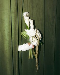 a person holding a bouquet of flowers in front of a green wall with vertical stripes