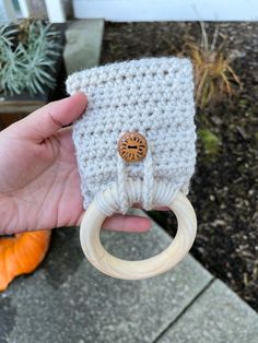 a hand holding a crocheted bag with a wooden ring in it's palm