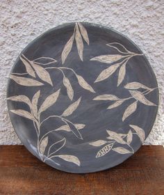 a black and white plate sitting on top of a wooden table next to a wall