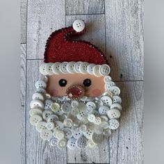 a santa clause made out of buttons on top of a wooden floor next to a wall