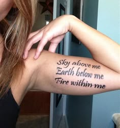 a woman with a tattoo on her arm that says, stay above me earth below me fire within me