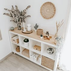 a white shelf with baskets and plants on it