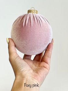 a hand holding a pink ornament in front of a white background with the words foxy pink on it