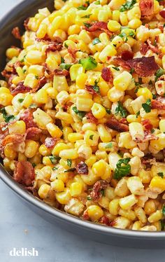 a bowl filled with corn and bacon on top of a table