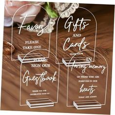 two clear acrylic gift cards sitting on top of a wooden table next to a flower