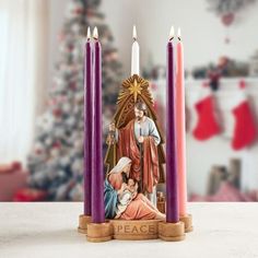 three candles with the image of mary and jesus on them in front of a christmas tree