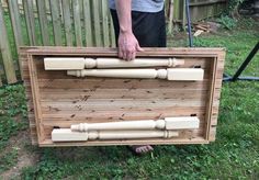 a man is holding a wooden box with bamboo sticks in it and the bottom section of the box has been made out of wood