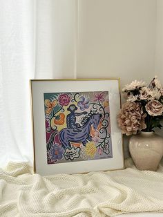 a vase filled with flowers next to a painting on top of a white bed covered in blankets