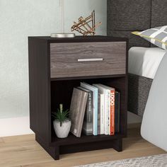 a nightstand with books on top of it next to a bed