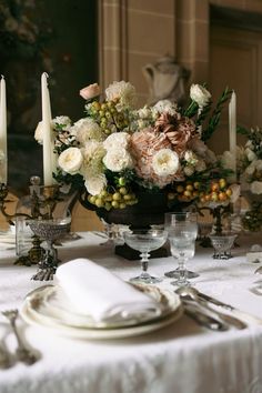 a table set with plates, silverware and flowers in a bowl on top of the table