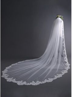 a wedding veil with flowers on the bottom and lace around the edge, hanging from a gray background