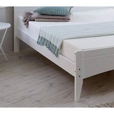 a white bed sitting on top of a wooden floor next to a table and chair