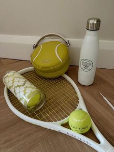 a tennis racket, ball and other items are on the floor next to a water bottle